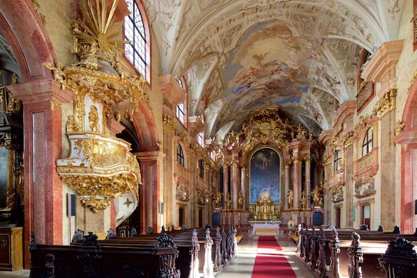 An ornate church interior with golden decorations, red carpet, and a high ceiling.