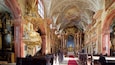 An ornate church interior with golden decorations, red carpet, and a high ceiling.