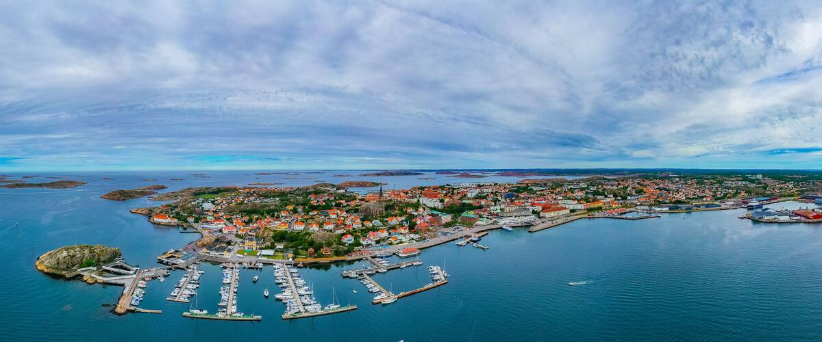 An aerial view of a coastal town with a marina, colorful houses, and a lighthouse.