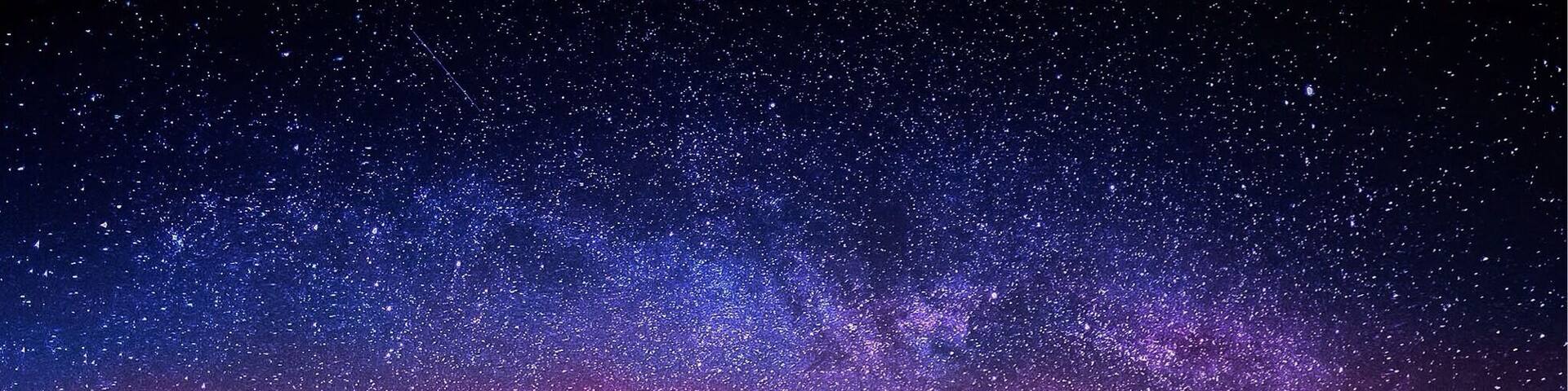 A green tent in a grassy field with a starry night sky.