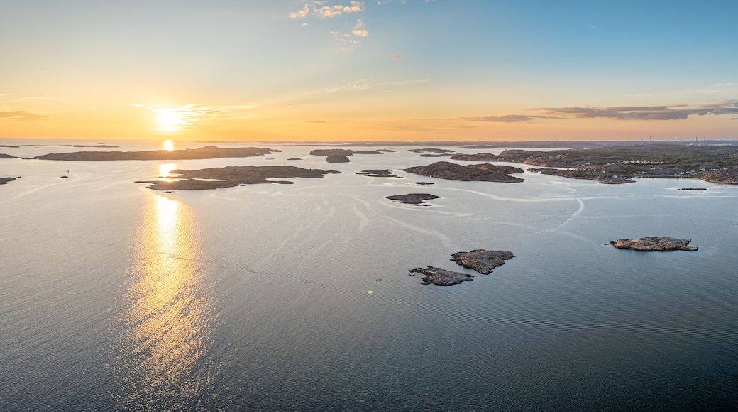 Un paisaje costero con un atardecer sobre un mar tranquilo, con islas dispersas y una costa lejana con edificios.