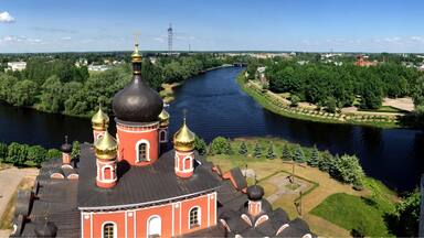 A river with a bridge, a church with golden domes, and a park with trees.