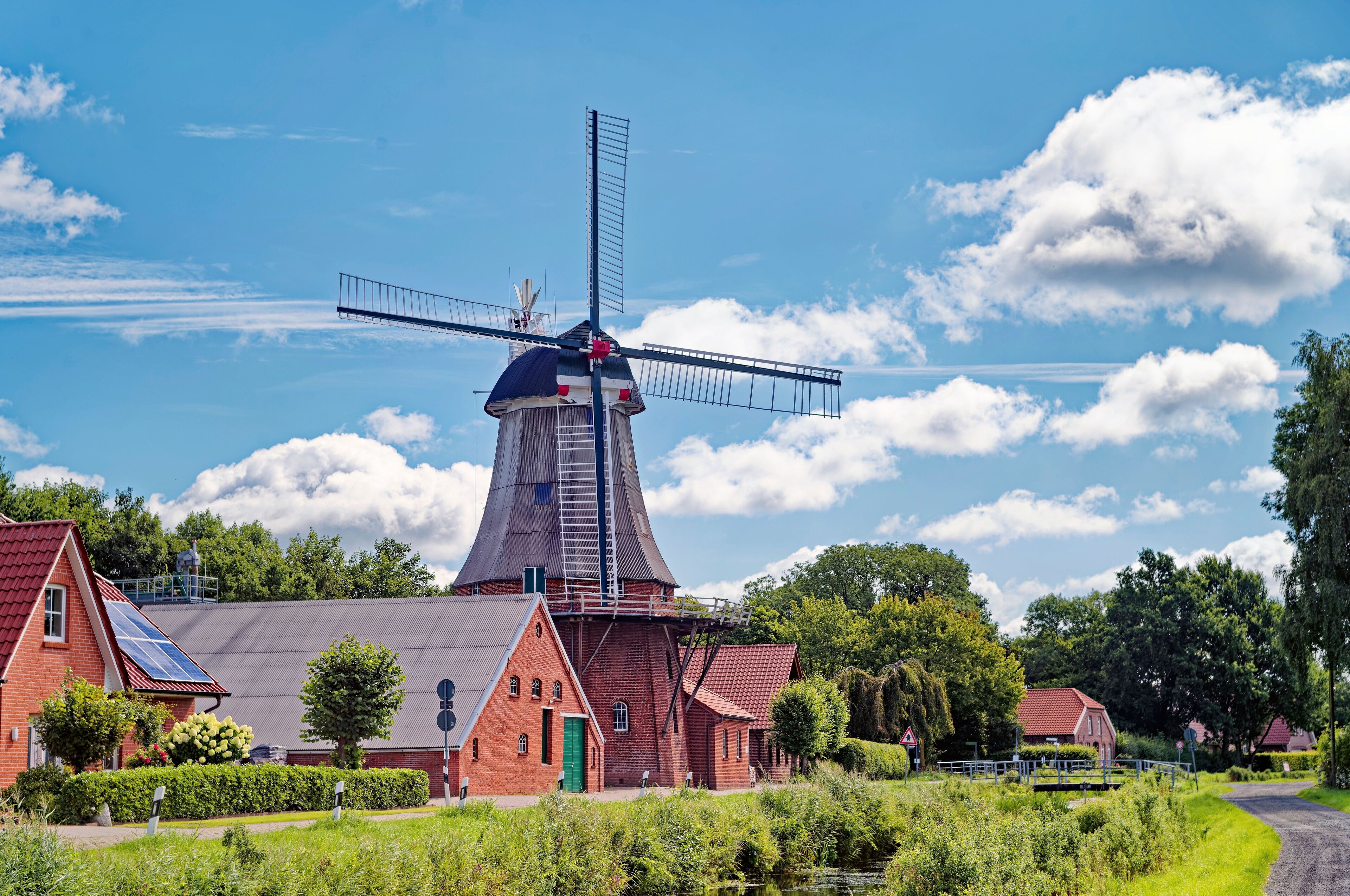 A windmill, red-roofed buildings, and a canal.