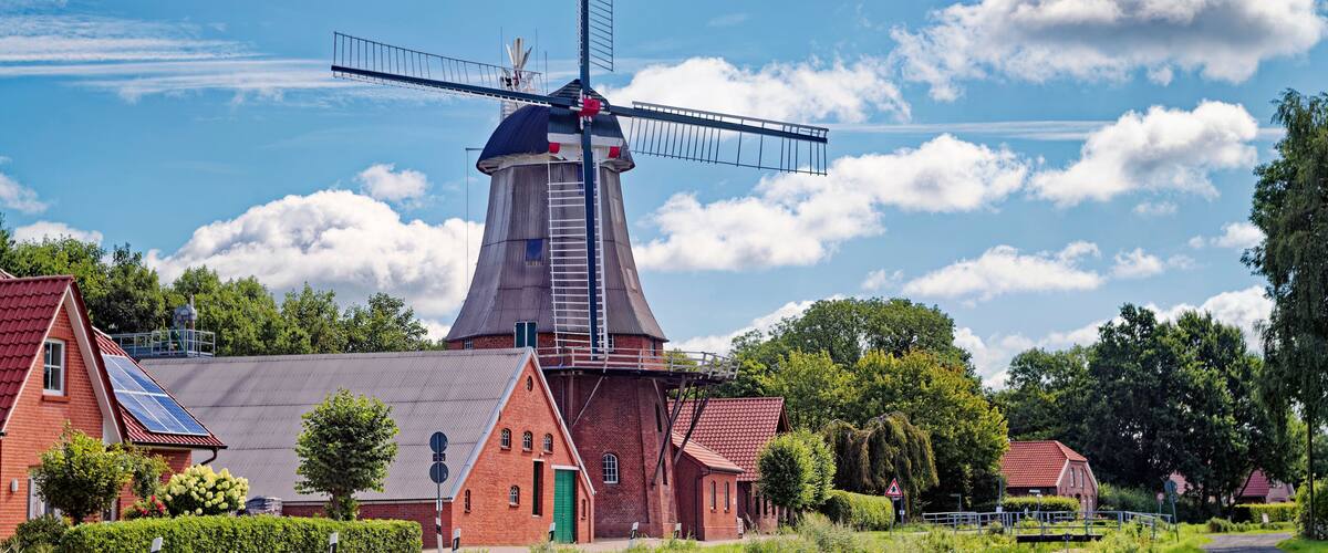 A windmill, red-roofed buildings, and a canal.
