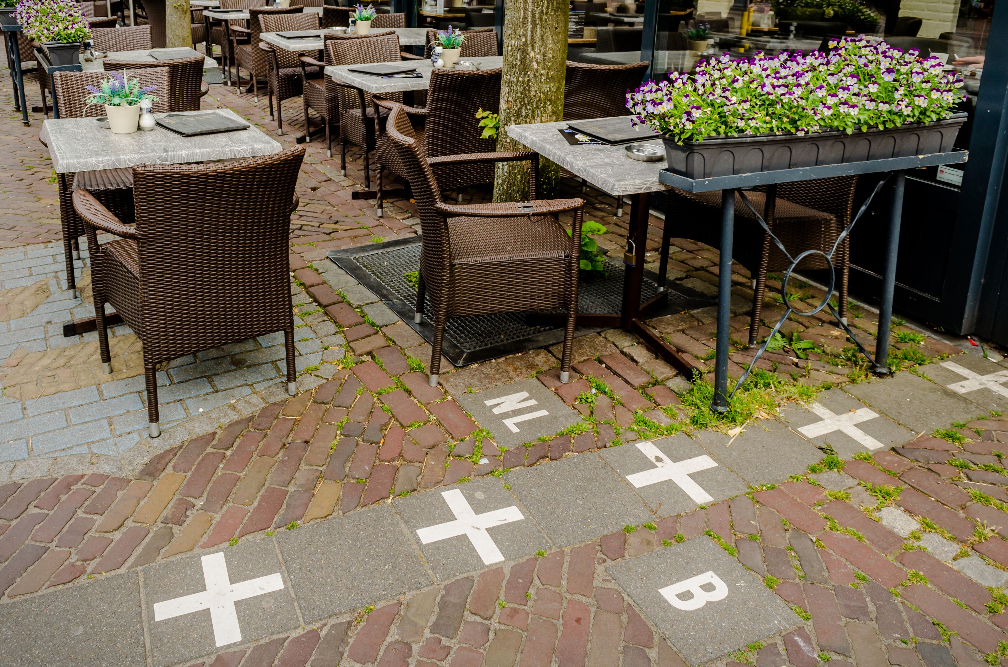 An outdoor café with wicker furniture, tables, and potted plants.