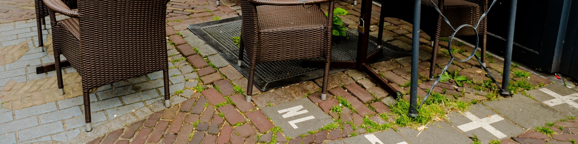 An outdoor café with wicker furniture, tables, and potted plants.