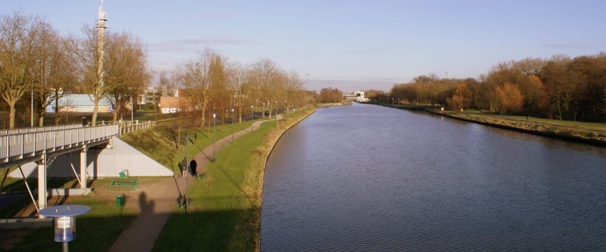 A river with a bridge, trees, and a tower in the background.