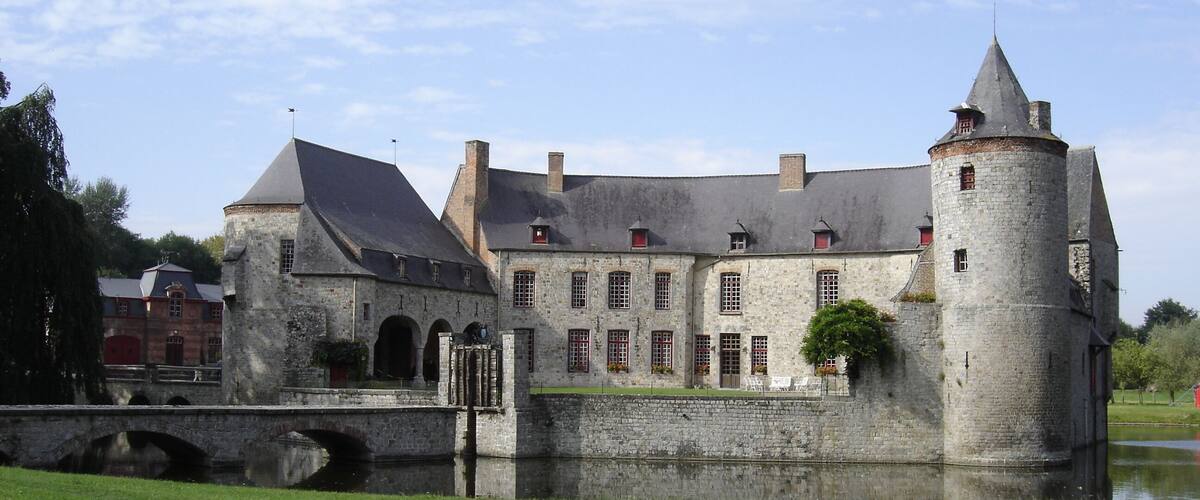 A historic stone castle with a moat, a bridge, and a tower.