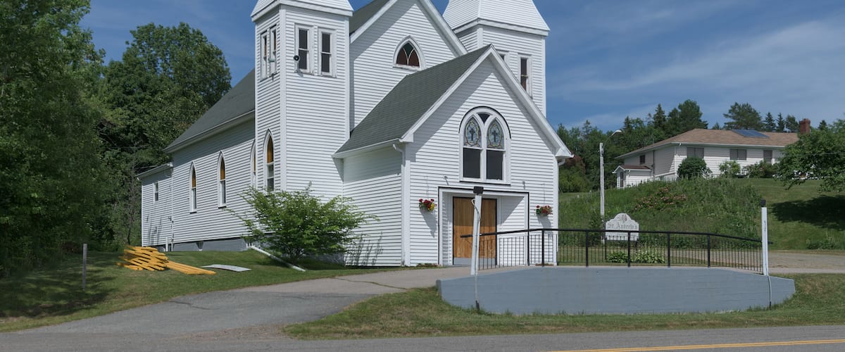 A white church with two steeples and a wooden door.