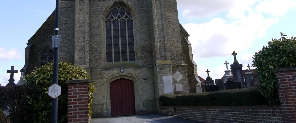 A tall church with a clock tower, a red door, and crosses in the background.