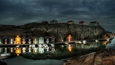 Um cais com casas coloridas e barcos refletidos em águas calmas.