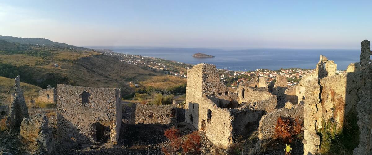Ancient stone ruins with a coastal town in the background.