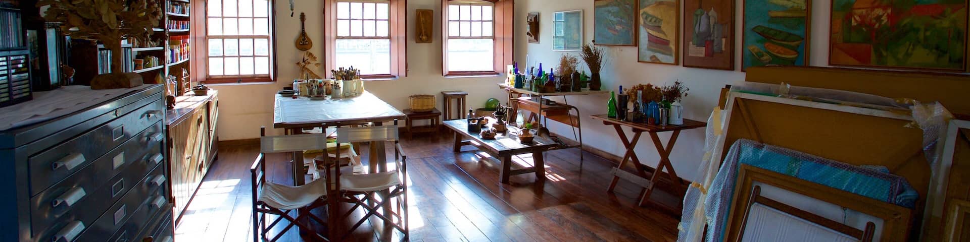 Una habitación amplia con suelos de madera, una mesa de comedor, sillas y varias obras de arte en las paredes.