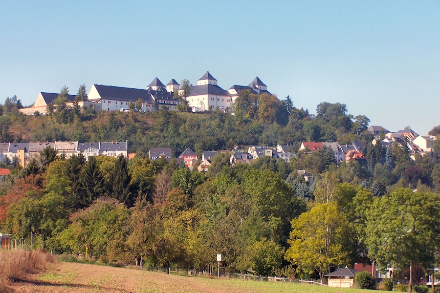 Um castelo numa colina, rodeado por casas e árvores.