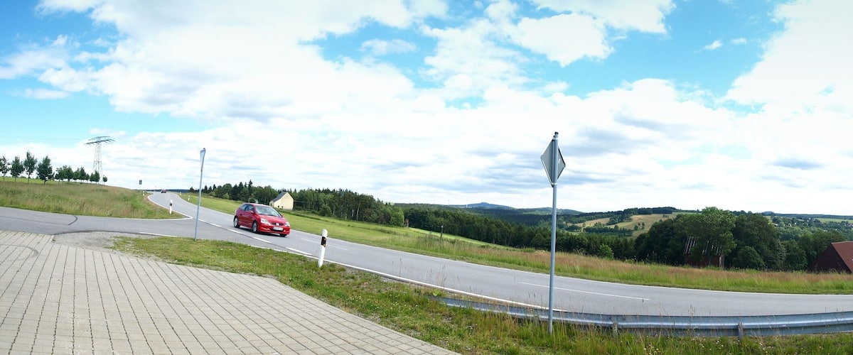 A winding road through a hilly landscape with a red car driving on it.