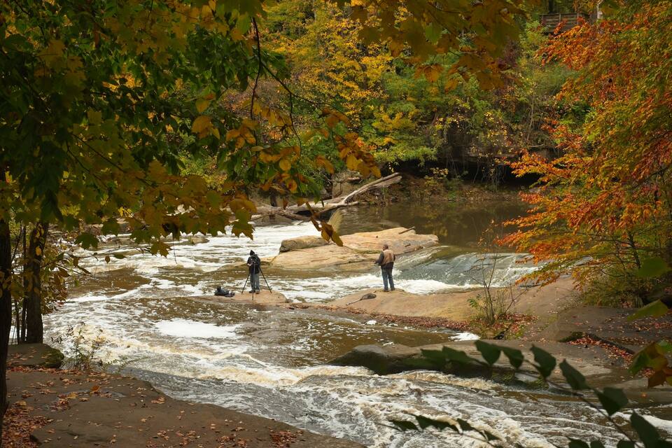 A river with people fishing, surrounded by autumn foliage.