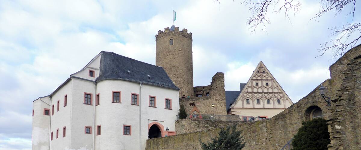 A castle with a white building and a stone tower.