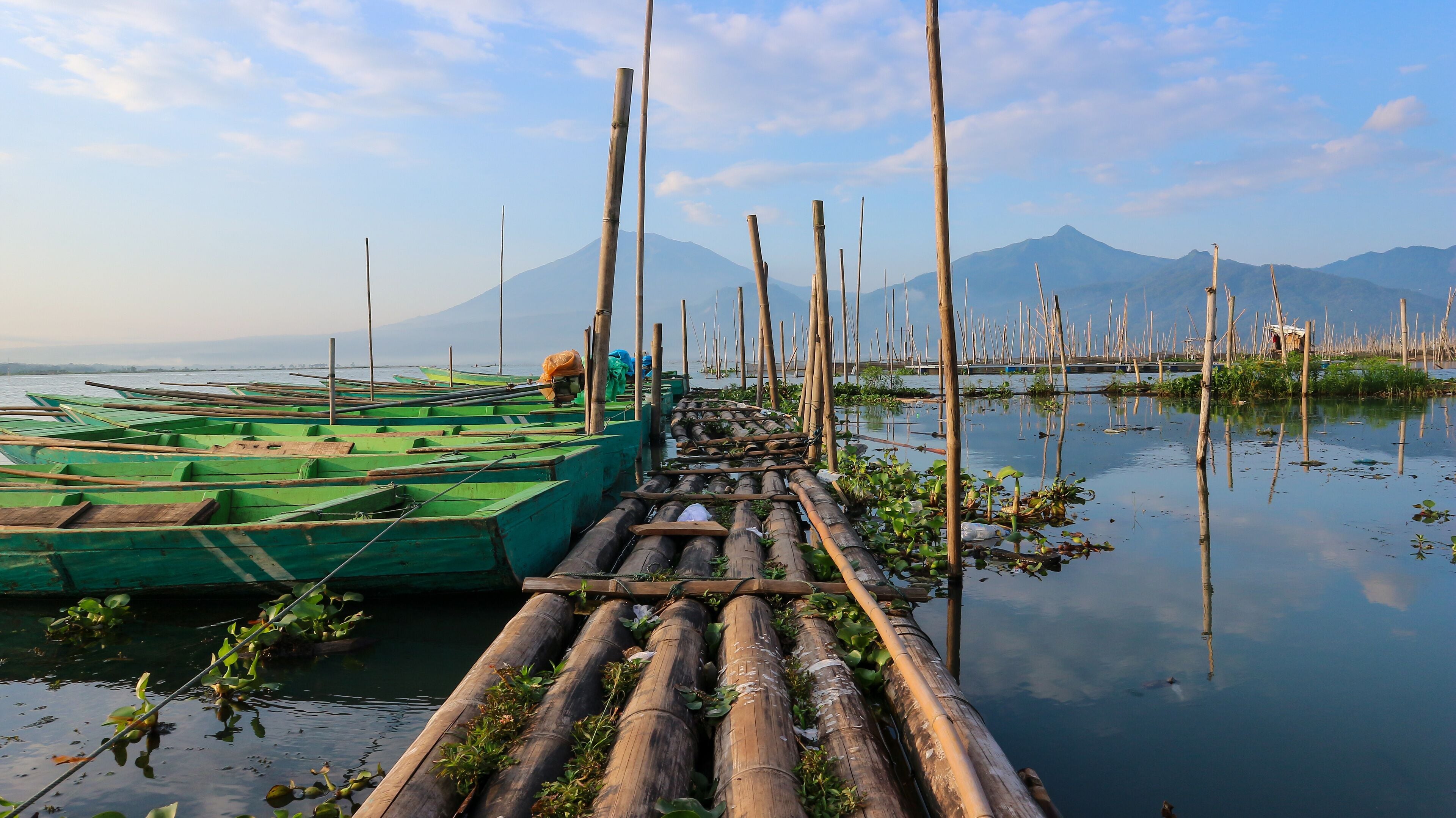 A bamboo raft docked at a calm river with mountains in the background.