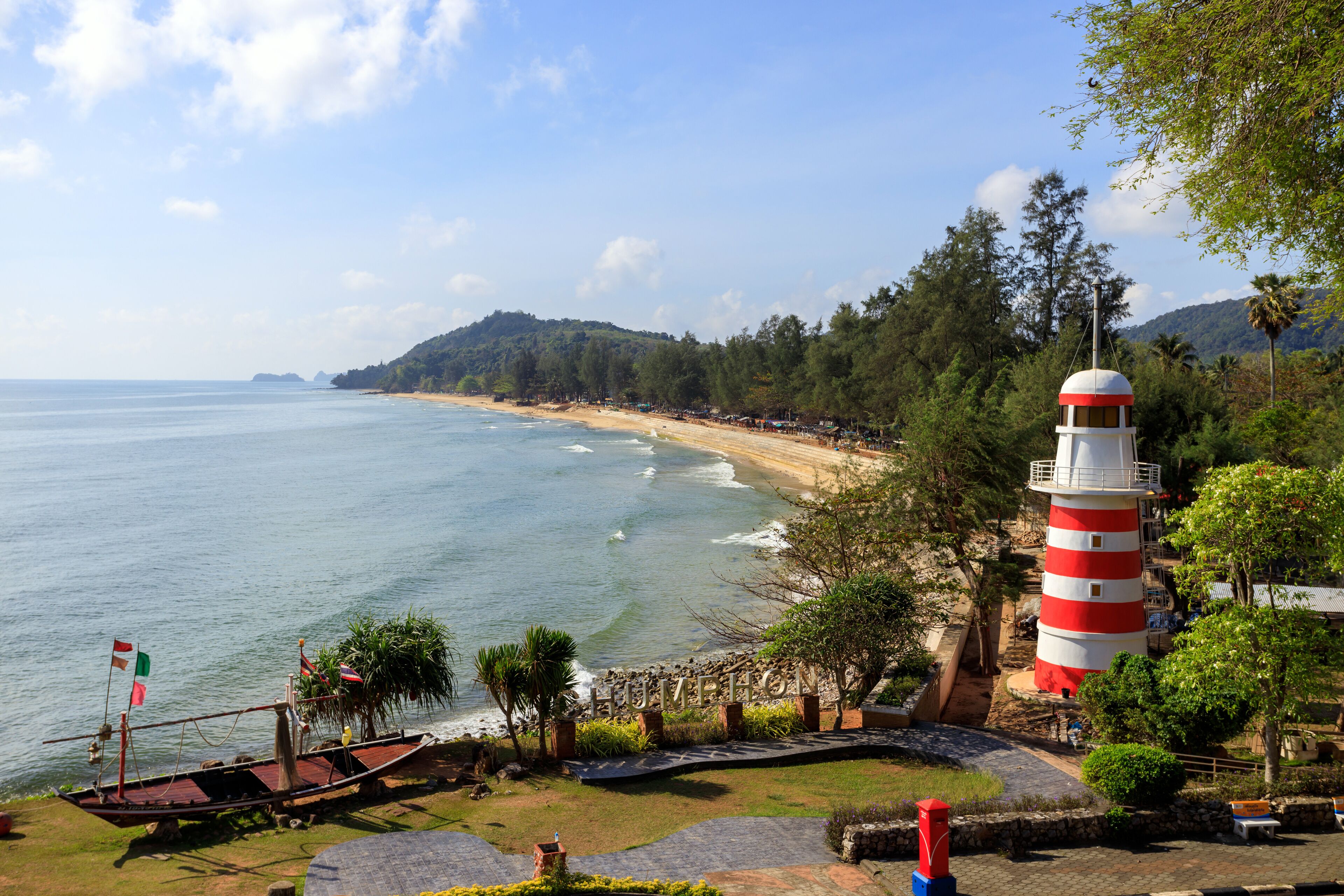 A coastal landscape with a lighthouse, beach, and rocky shoreline.