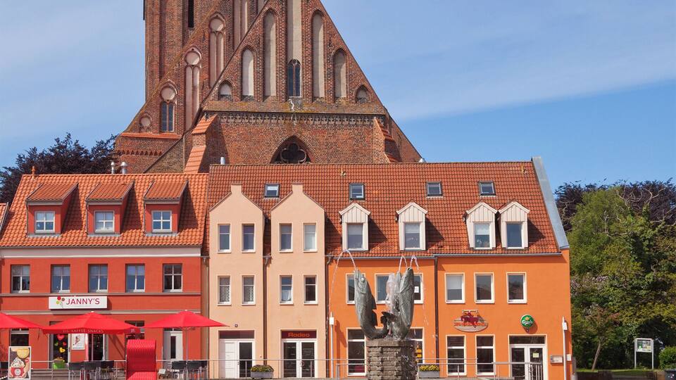 A church with a tall spire, a statue in front, and a red building labeled "Janny's".