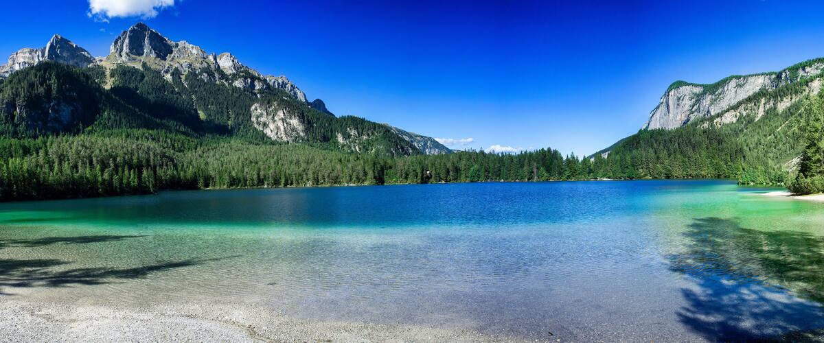 A mountain lake surrounded by forest and rocky cliffs.