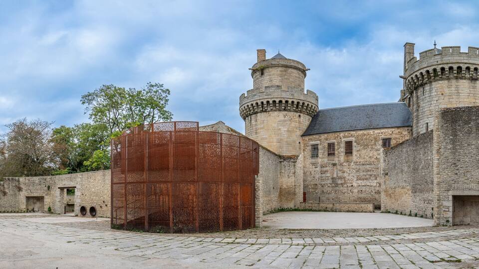 A historic castle with stone walls, two towers, and a large wooden gate.