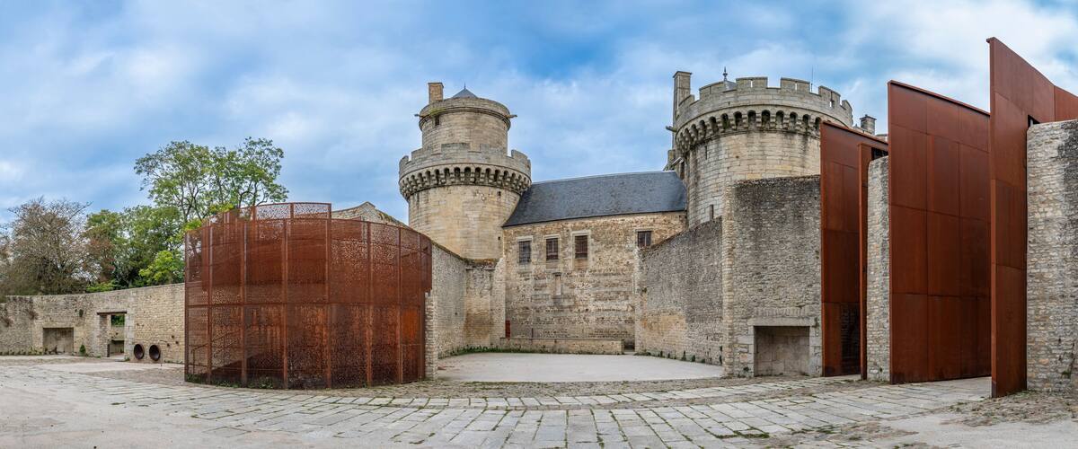 A historic castle with stone walls, two towers, and a large wooden gate.