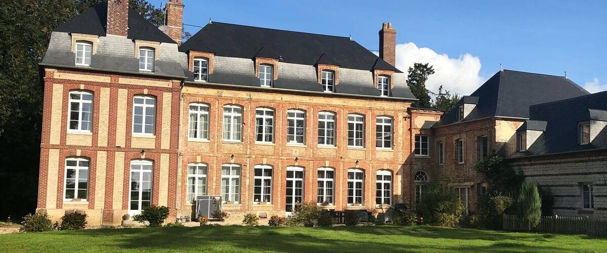 A large brick building with multiple windows and a green lawn in front.