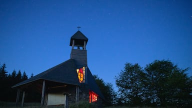 A church with a cross on top, a steeple, and a stained glass window.