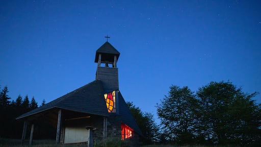Una iglesia con una cruz en la parte superior, un campanario y una vidriera.
