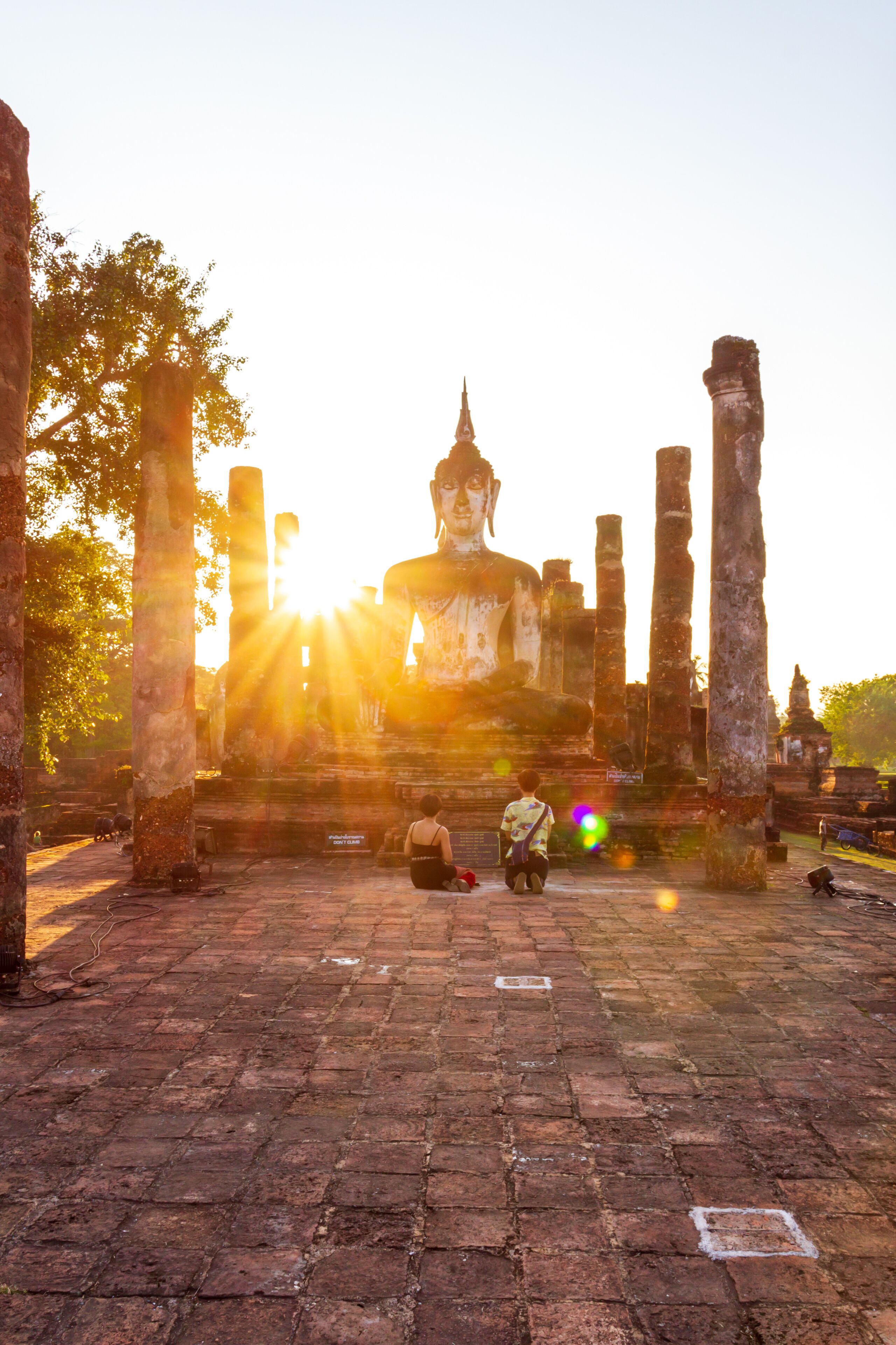 LGBT couples tourist blessing  Buddha in Sukhothai historical park, Thailand.