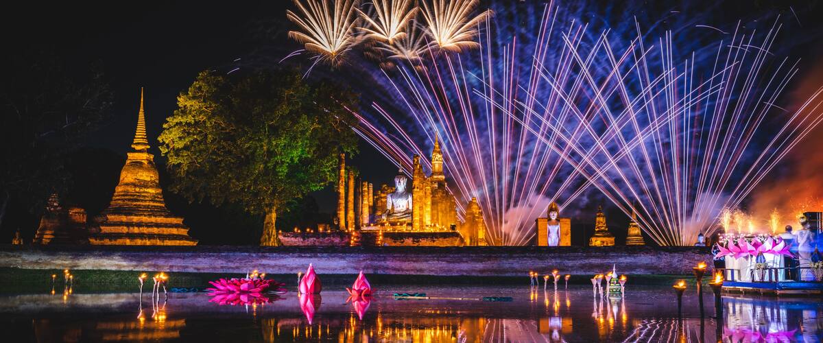 A night scene with a temple, lotus flowers, and fireworks.
