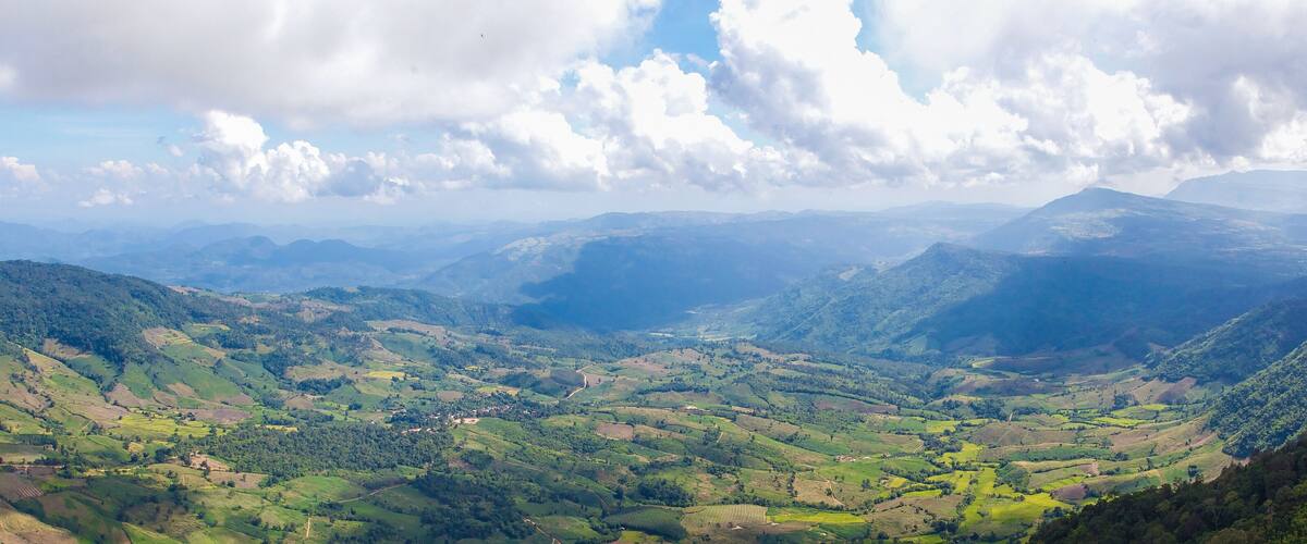 A mountainous landscape with rolling hills, valleys, and a winding road.