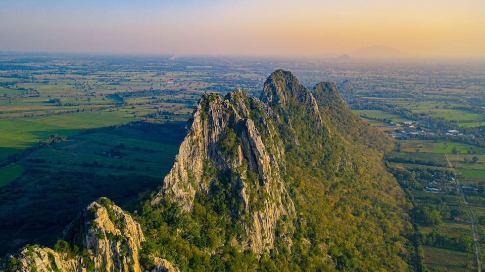 A rugged mountain range with dense vegetation and a vast valley below.
