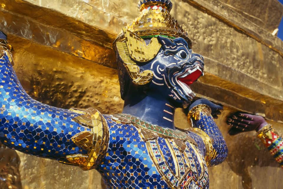 Una estatua azul y dorada con un extremo puntiagudo, ubicada frente a una estructura de piedra.