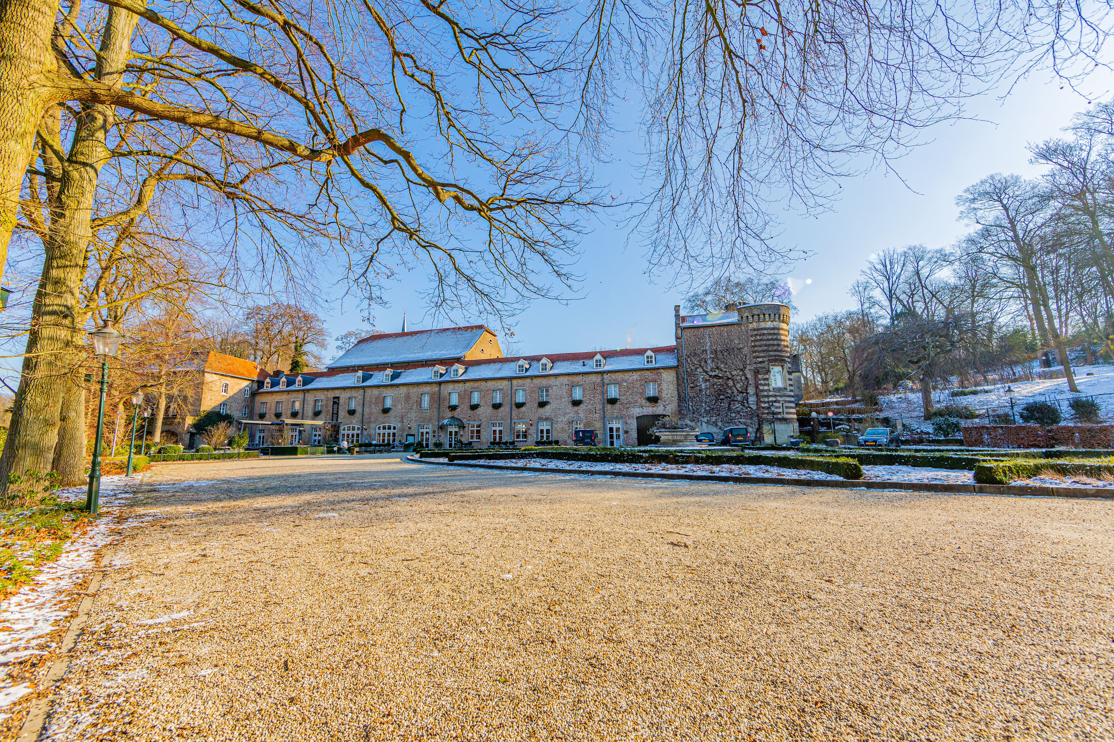 Esplanade with Elsloo castle, bare trees and traces of snow in the background, sunny winter day with a blue sky in Elsloo, South Limburg, Netherlands