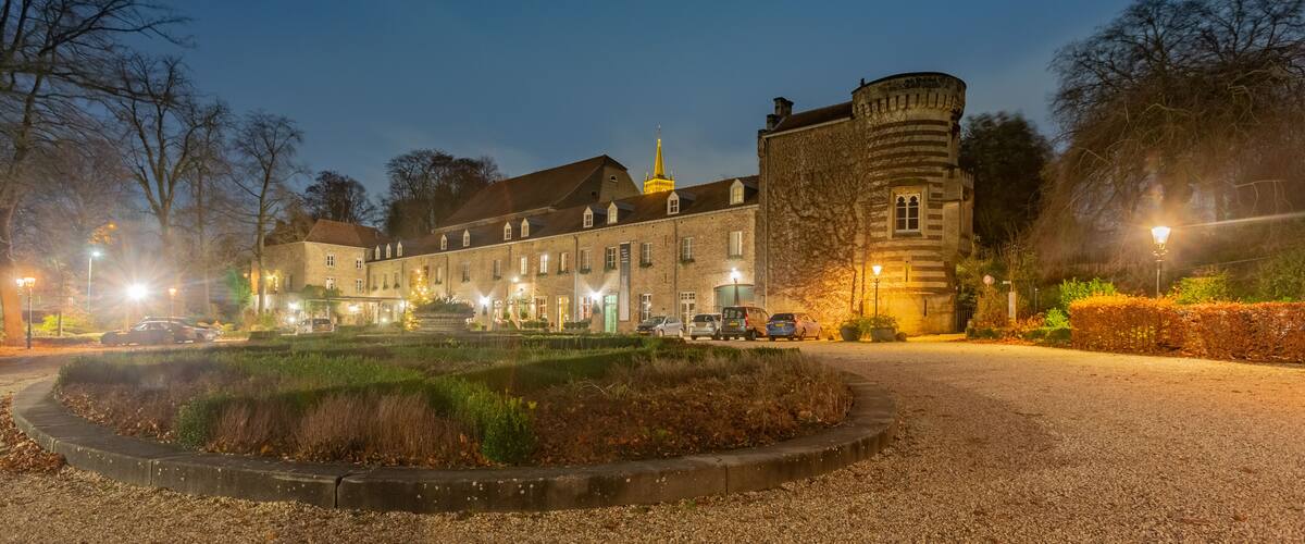 A historic building with a tower, surrounded by a well-maintained garden and a gravel path.