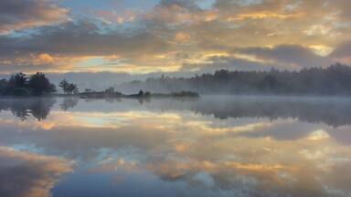 A calm lake reflecting the sky and trees.