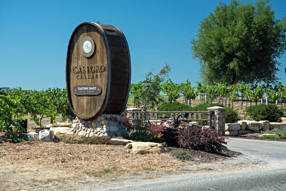 A wooden barrel-shaped sign for Castoro Cellars with a tasting schedule.