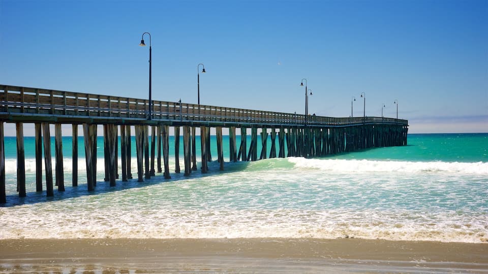A long pier extending into the ocean with waves crashing against it.