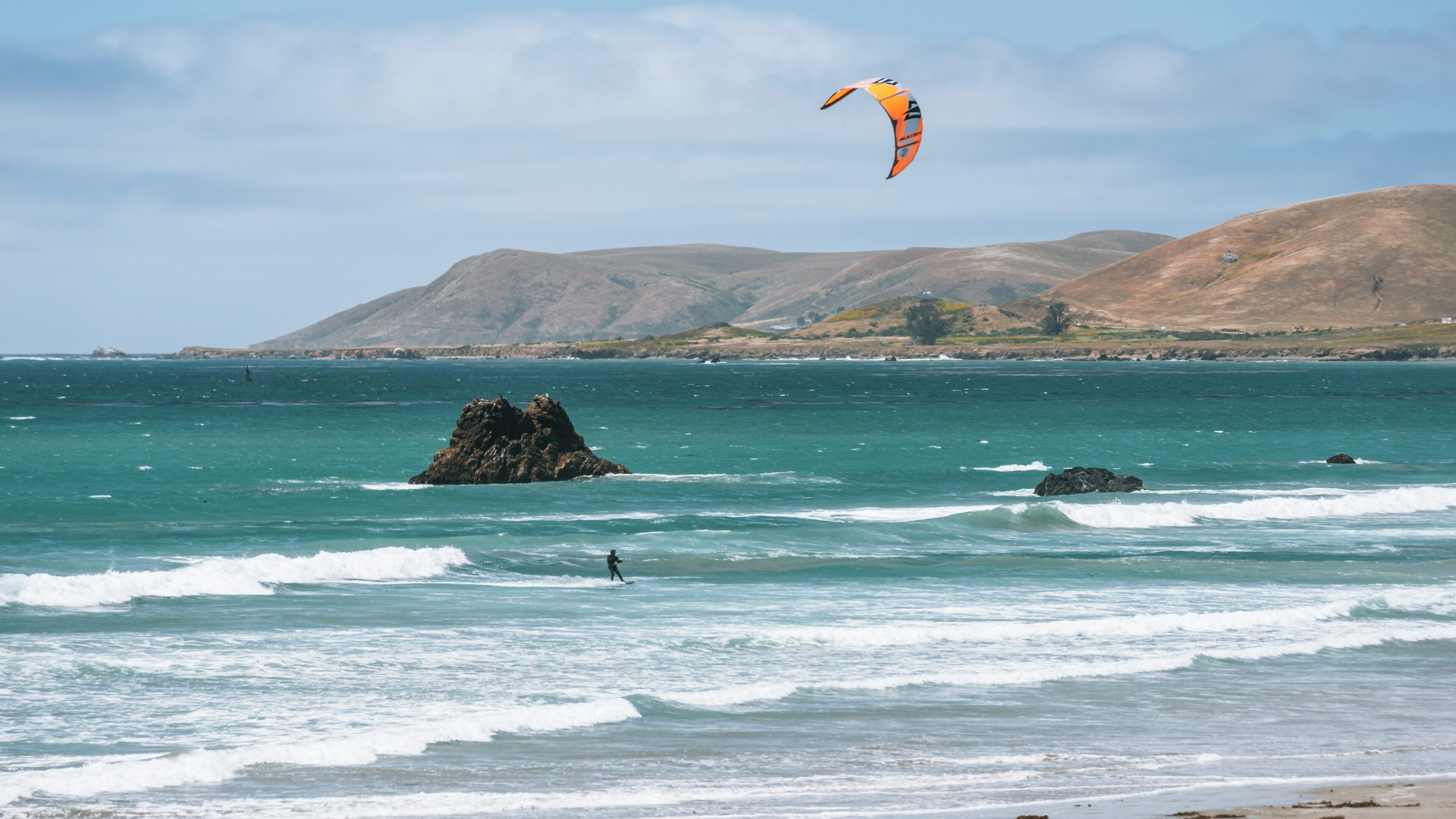 Kite surfer enjoys vibrant waters of Morro Strand State Beach in Morro Bay, California during a sunny afternoon