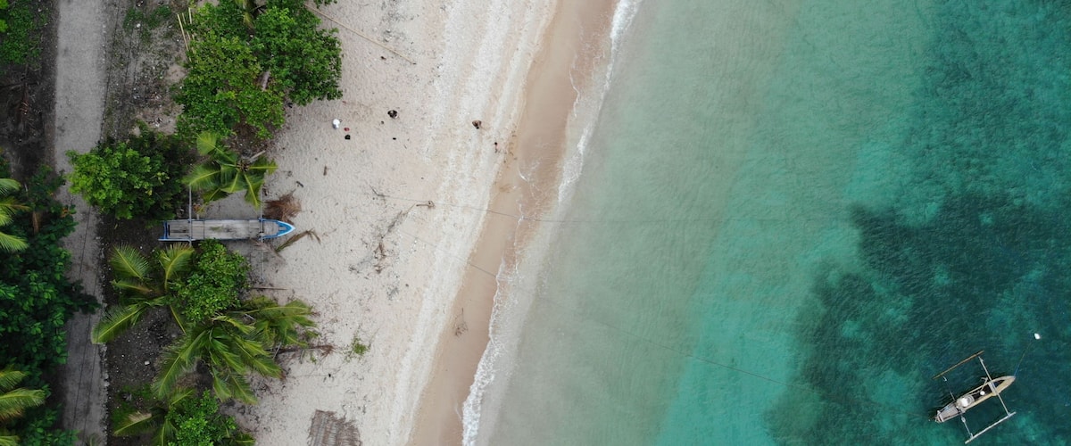 Aerial view of the turquoise bay with boats. Baucau, East Timor.