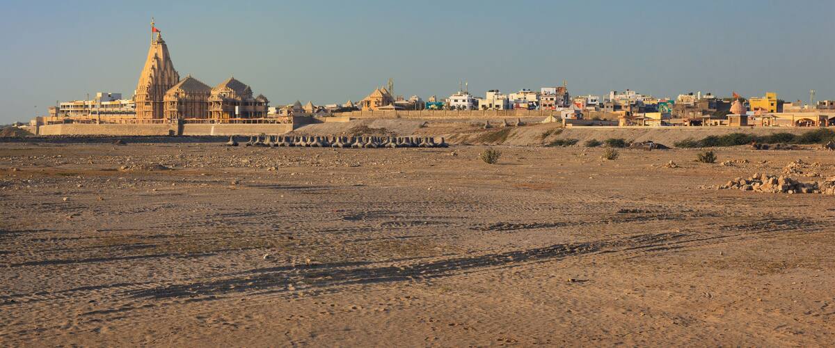 A desert landscape with a prominent historical building with a tall spire and domed structures.