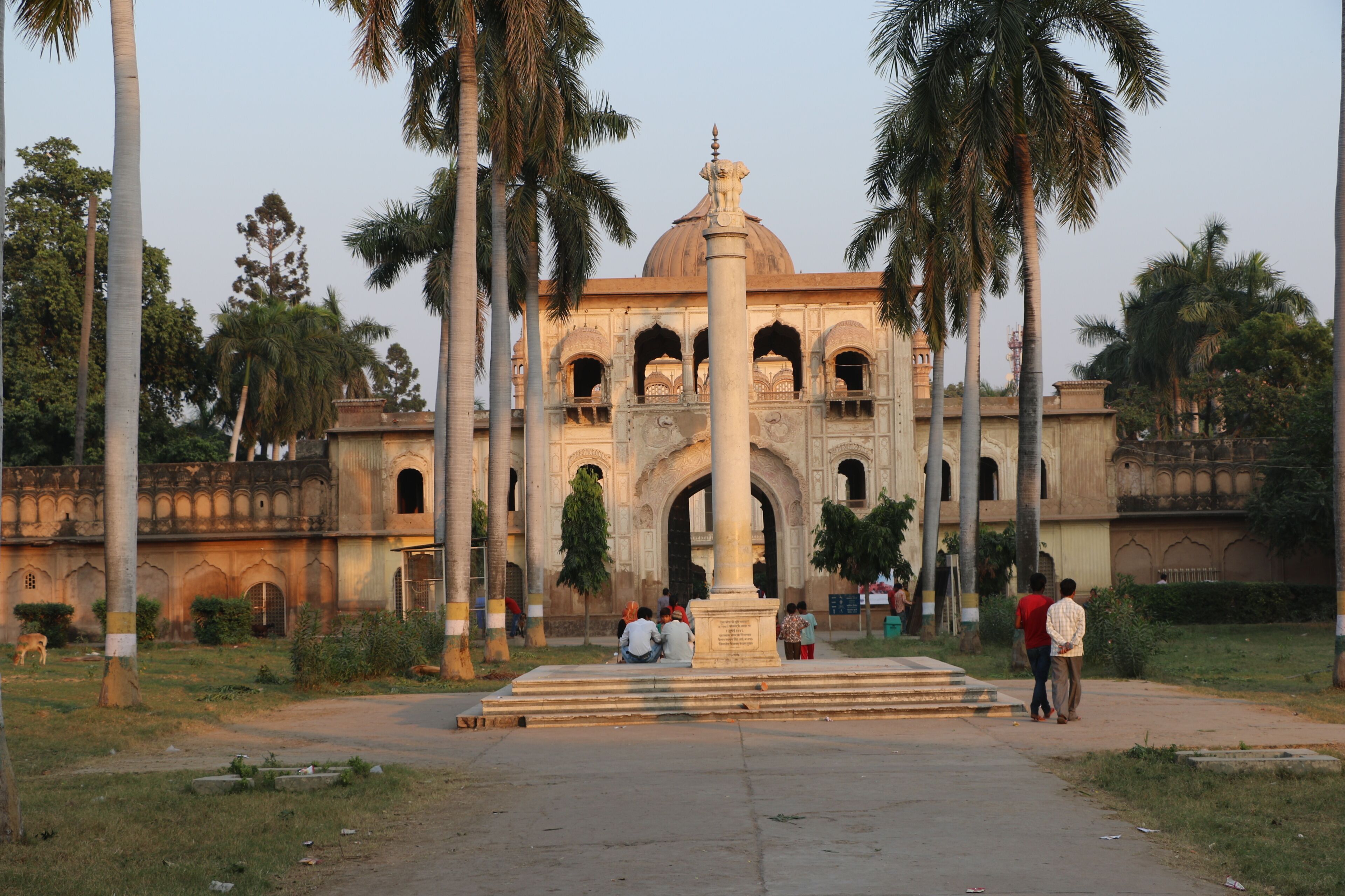 A historical building with a dome and arches, surrounded by palm trees.