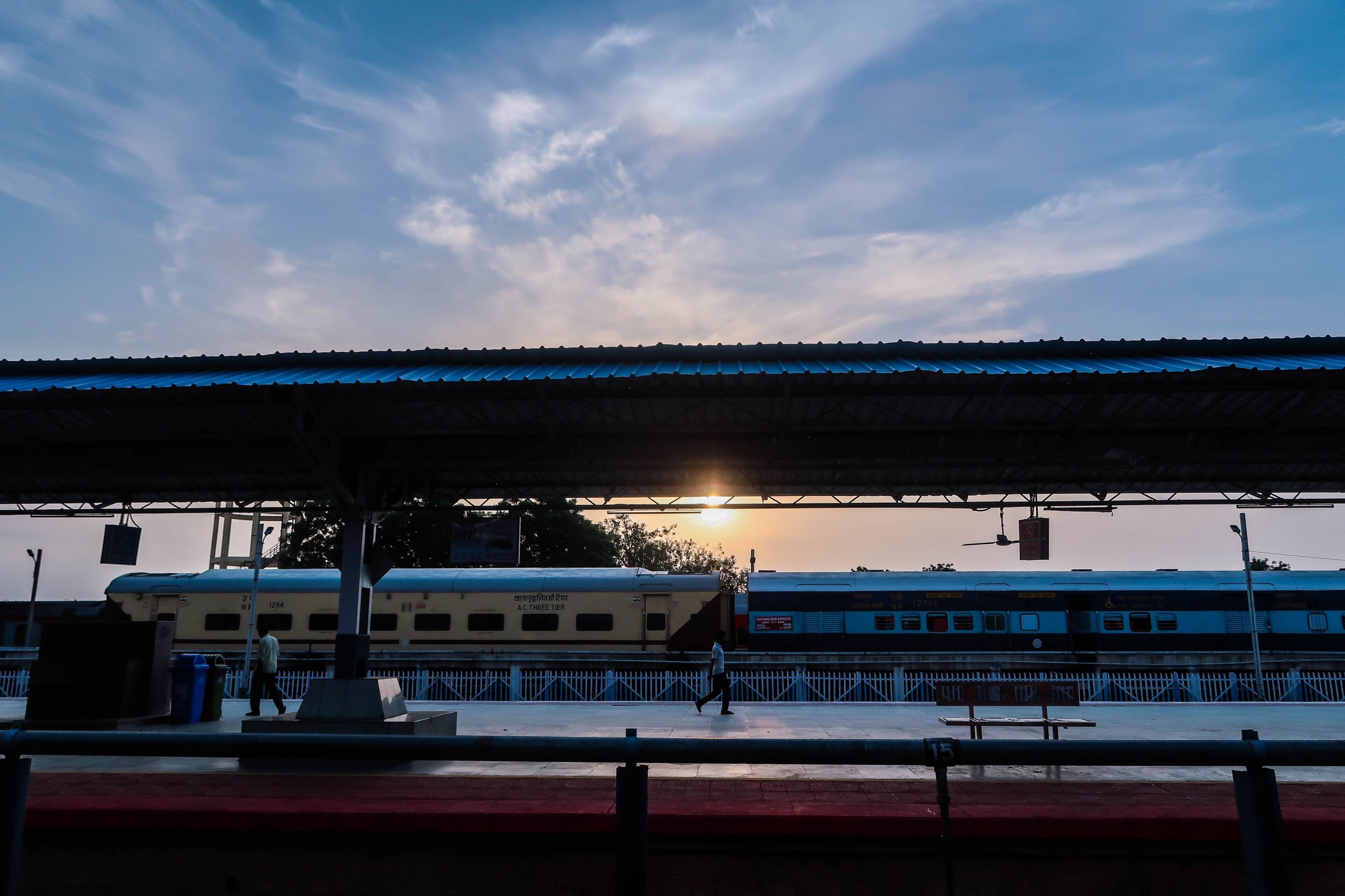 A train station with a covered platform and a train in the background.