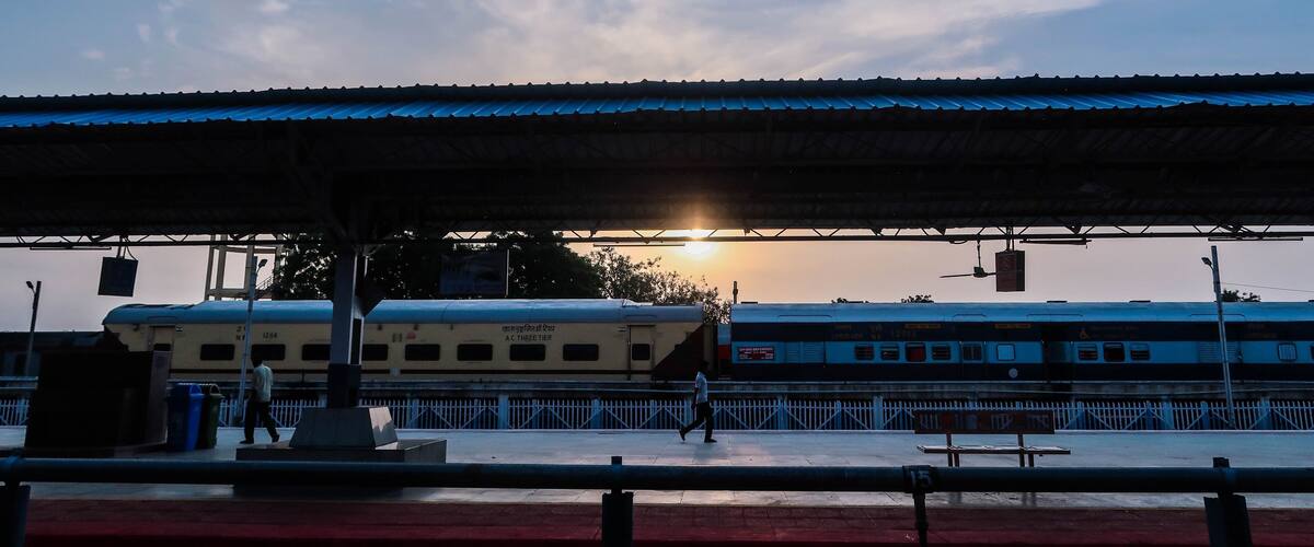 A train station with a covered platform and a train in the background.