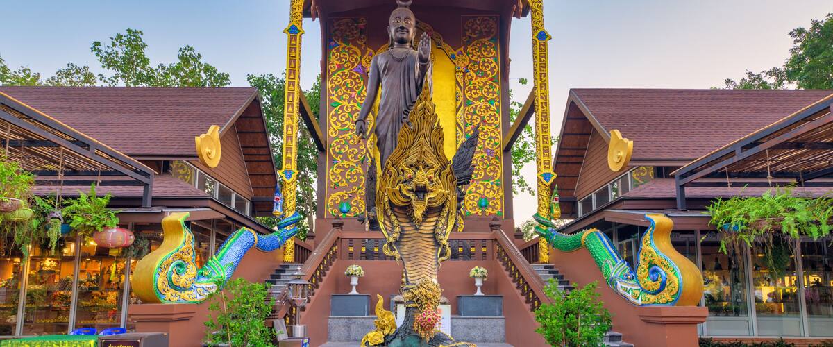 A large Buddha statue under a golden pavilion with intricate designs.