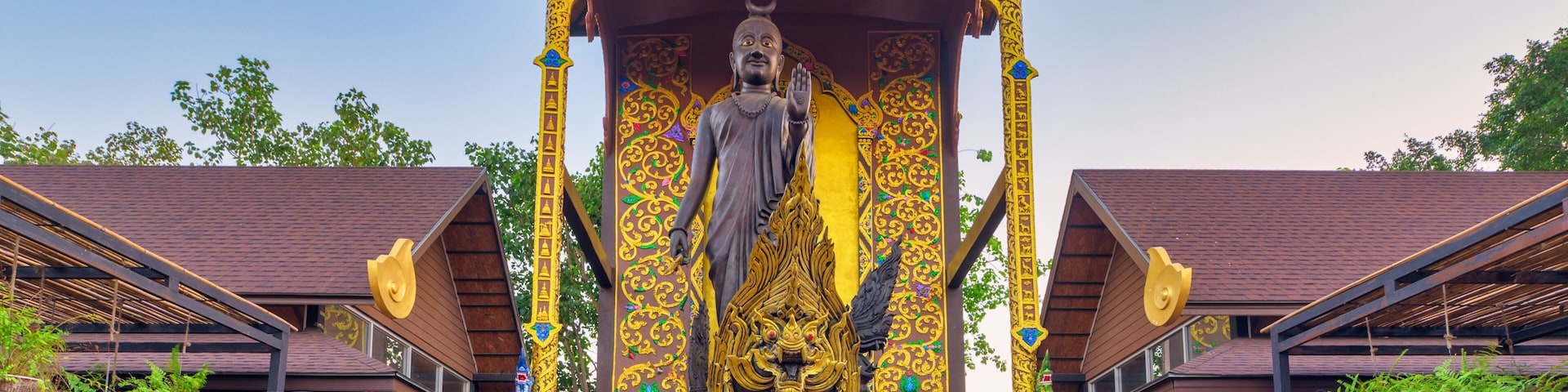 A large Buddha statue under a golden pavilion with intricate designs.