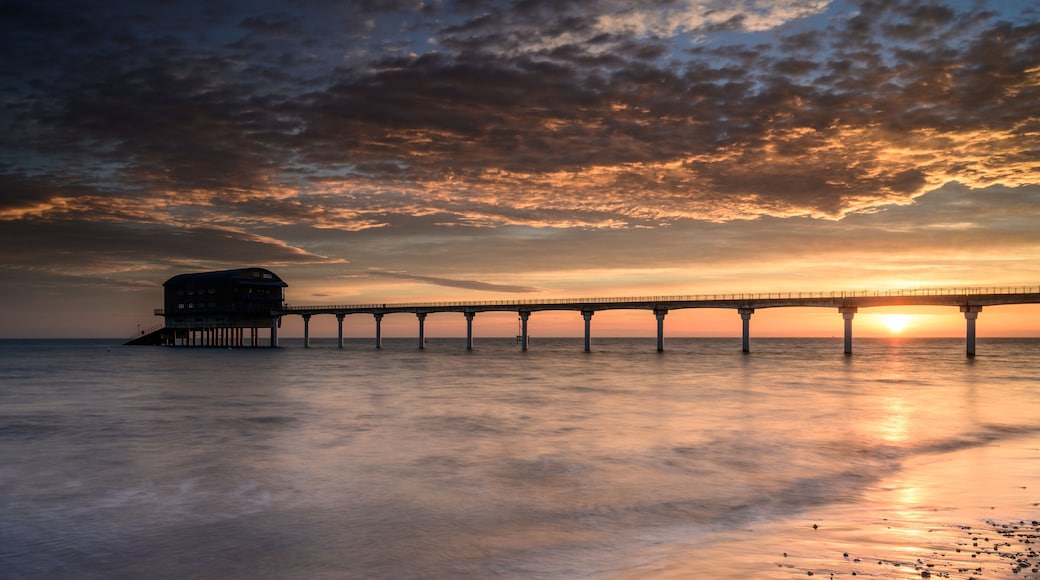 A pier extending into the water with a sunset in the background.