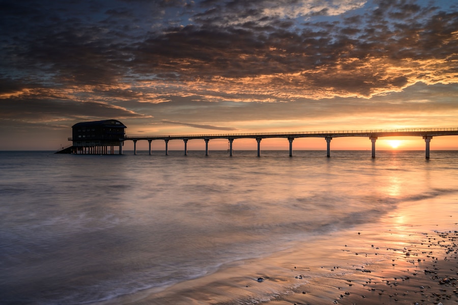 A pier extending into the water with a sunset in the background.